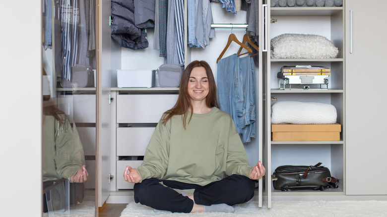 Happy woman meditating in front of organized closet