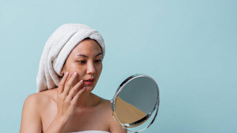 Woman looking at her face in the mirror 