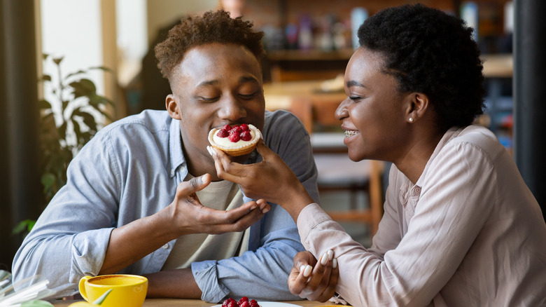 Woman feeding date a pastry