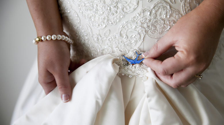 Bride pins blue bird charm to her dress