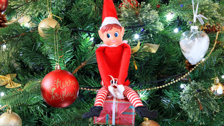 Elf toy sitting on Christmas tree branches