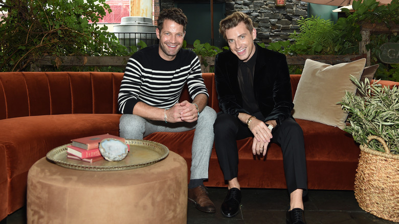 Nate Berkus and Jeremiah Brent smiling on a couch