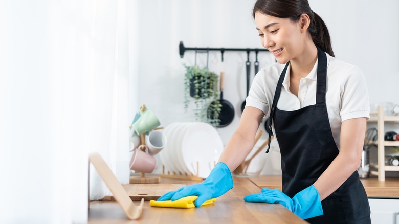 A smiling woman wearing rubber kitchen gloves