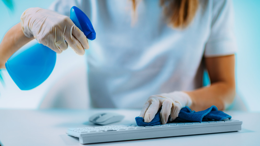 Woman disinfecting computer keyboard