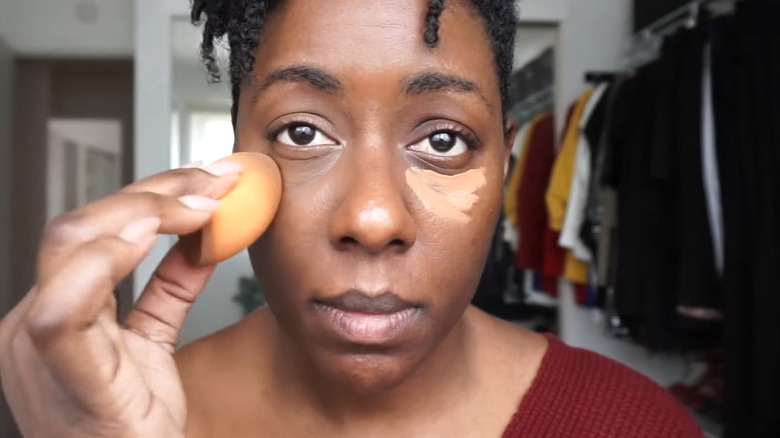 black woman applying concealer