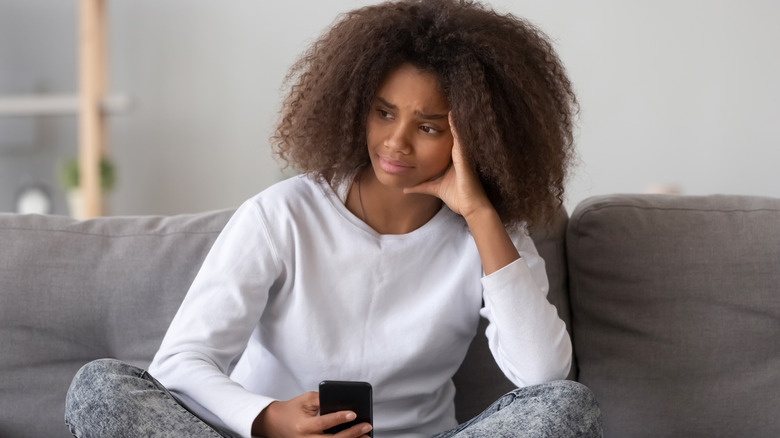 Sad girl with phone on couch