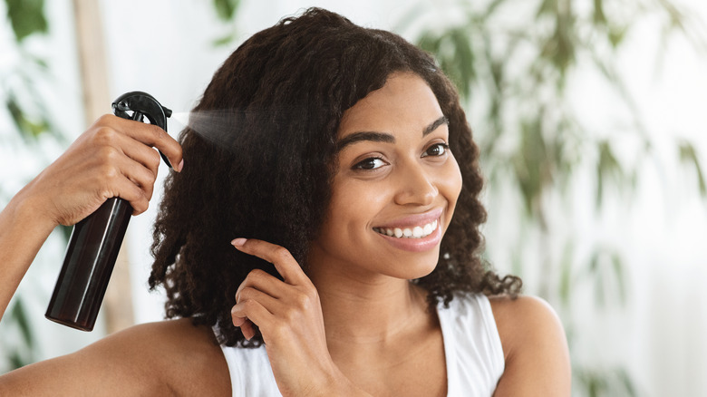 Woman spraying hair oil