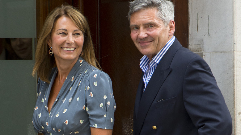 Carole and Michael Middleton pose on their doorstep in business chic clothes