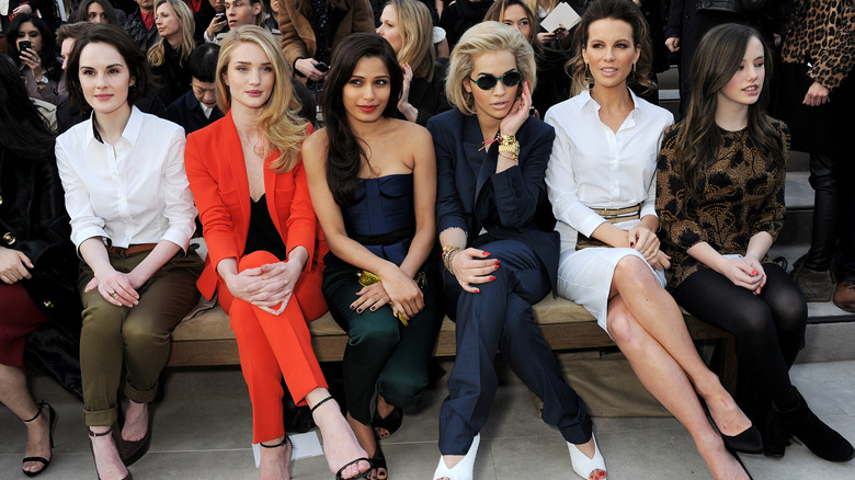 Lily Mo Sheen sitting next to several stars at a fashion show