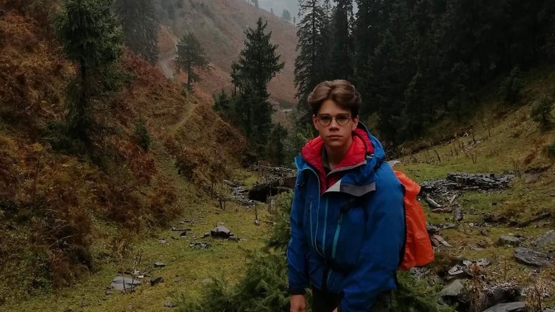 Sam Chatto stands on a mountain in India surrounded by trees