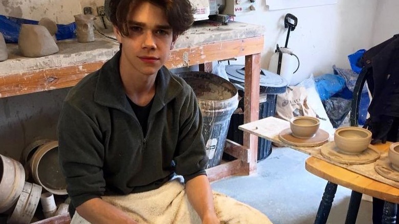 Samuel Chatto sits in a pottery studio surrounded by clay pots