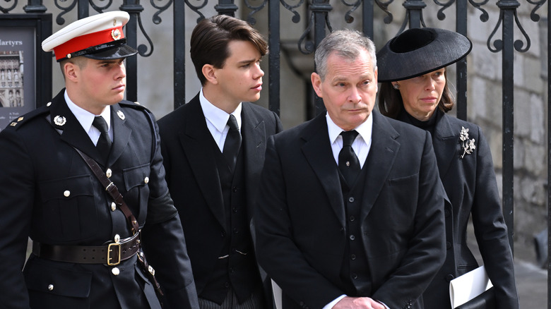 Sam Chatto and his immediate family stand in all black outside of black gates for the queen's funeral