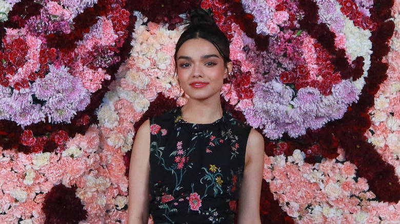 Rachel Zegler standing in front of artwork at a fashion show