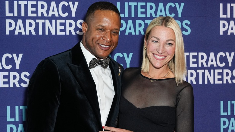 Craig Melvin wears a fitted tuxedo and bowtie smiling next to his wife at a Literacy Partners event