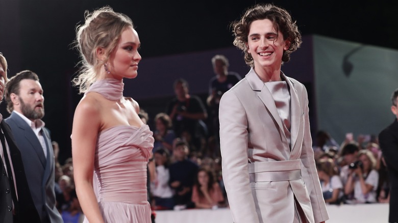 Lily-Rose Depp in a pink dress and Timothee Chalamet in a grey suit on a red carpet