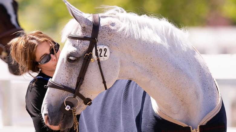 Hannah Selleck stands outside looking at a white horse