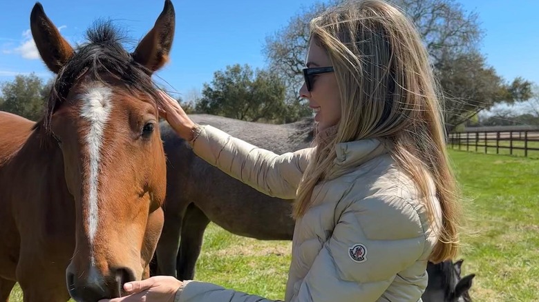 Hannah Selleck petting a brown horse