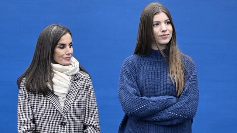 Queen Letizia and Infanta Sofía standing next to each other against blue background