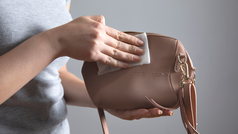 Woman cleaning leather purse