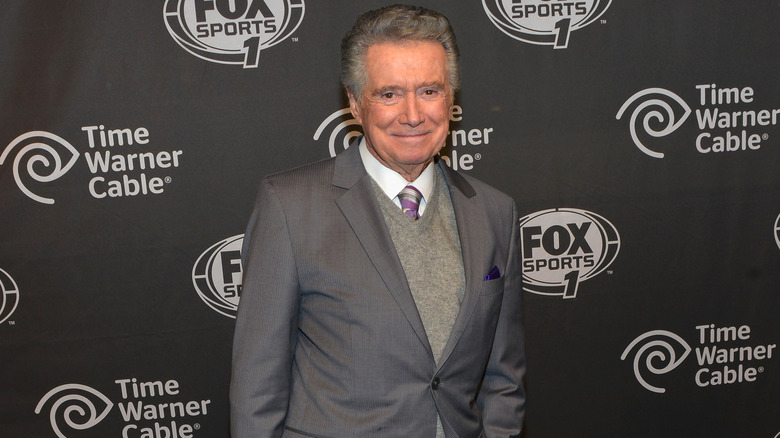 Regis Philbin stands for a picture in a grey suit