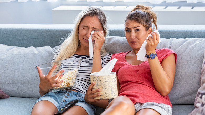 Two women crying while watching a movie. 