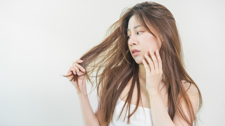 Woman looks at hair concerned