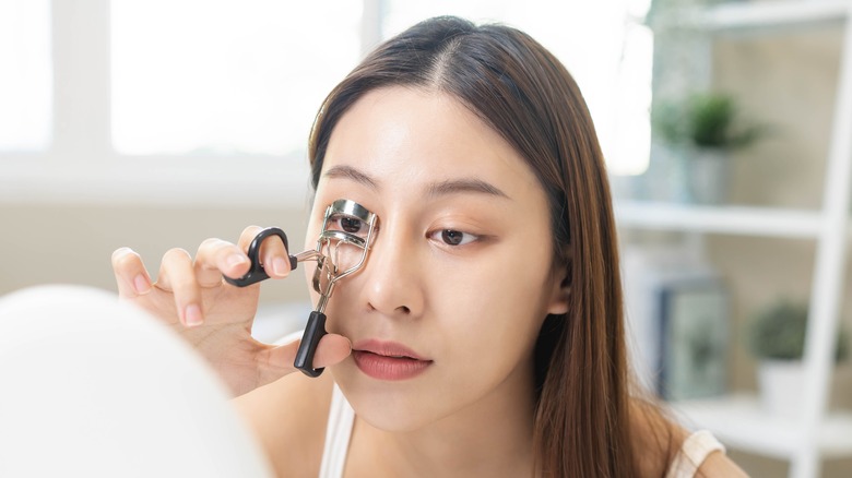 Woman curling her eyelashes