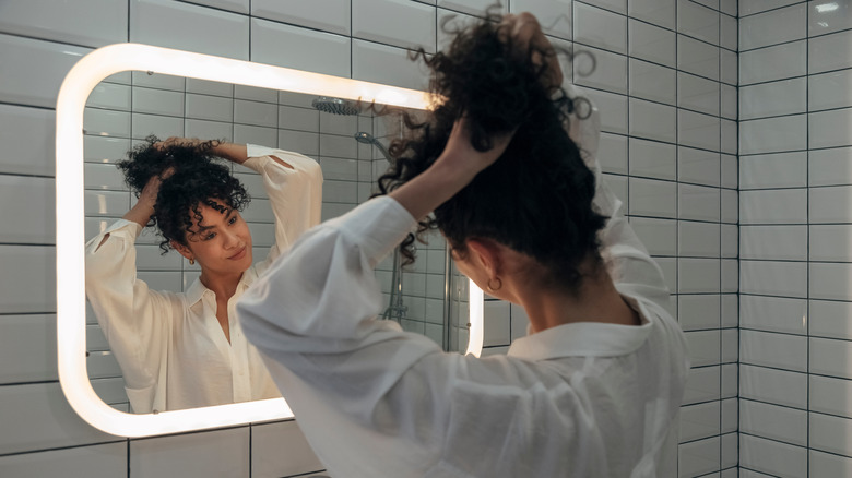 Woman styles her hair in a mirror