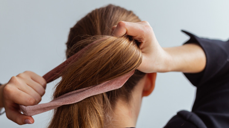 Woman tying her hair with a scrunchie