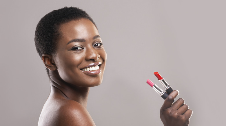 Woman smiles holding lipstick