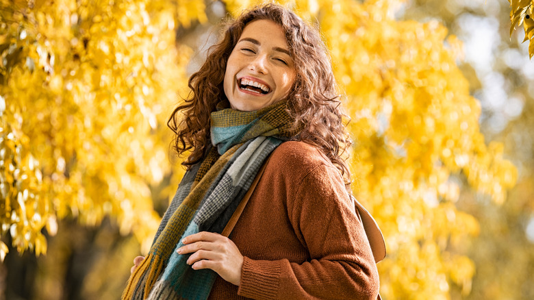 Woman smiling, wearing sweater and scarf