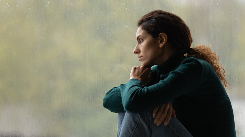 Woman looks out of window sad