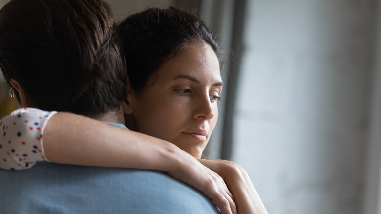 Woman hugs man looking sad