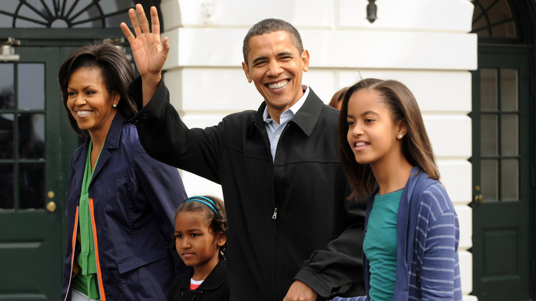 Barack Obama waving as he walks with his family at the White House