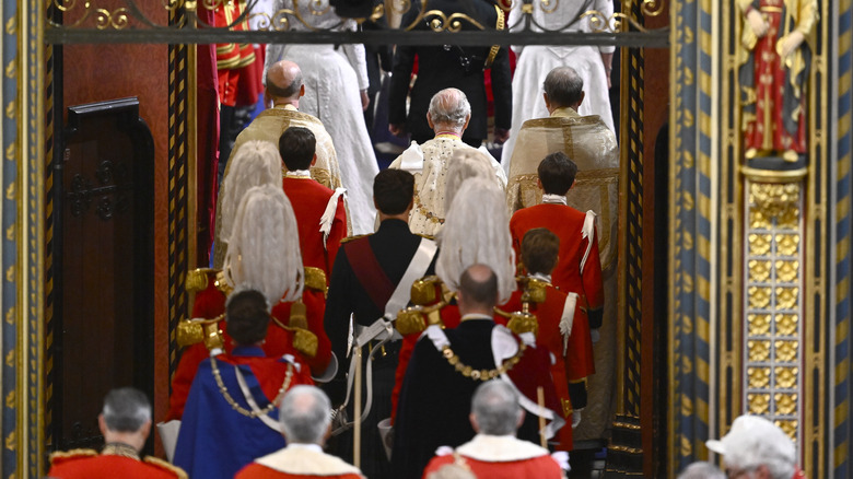 King Charles III entering his coronation with Prince William and Kate behind him