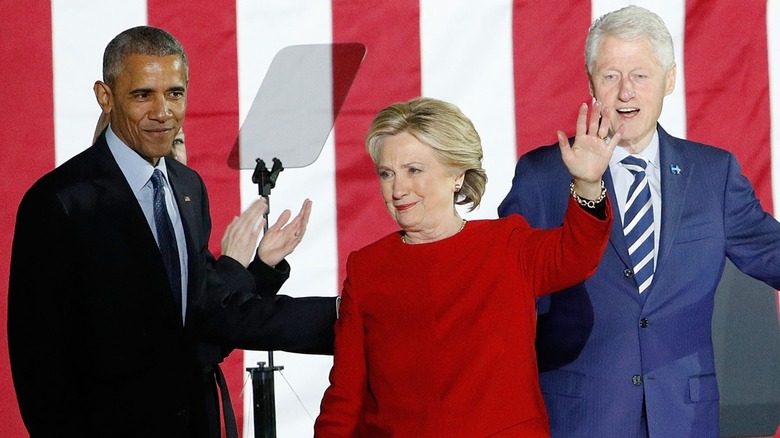 Barack Obama, Hillary Clinton, and Bill Clinton standing onstage and smiling