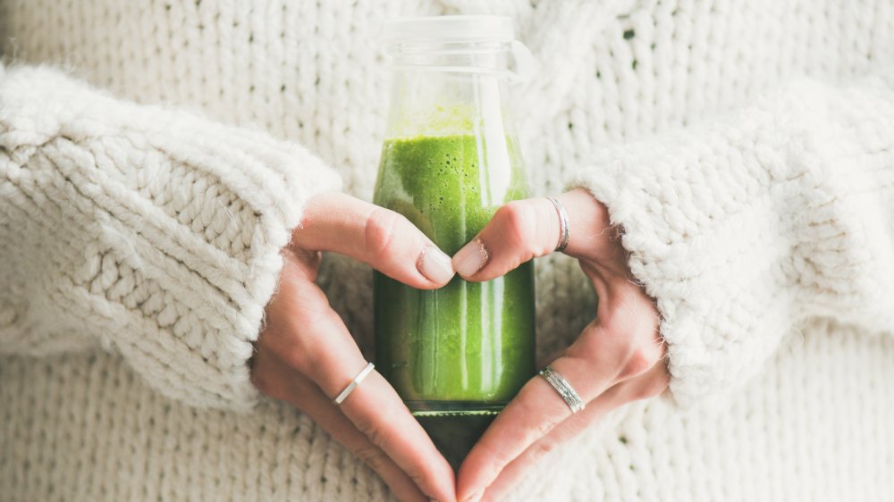 Woman holding a bottle of green juice