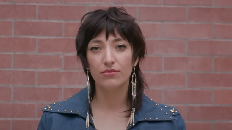 Young woman with short hair, long earrings and a blue leather jacket