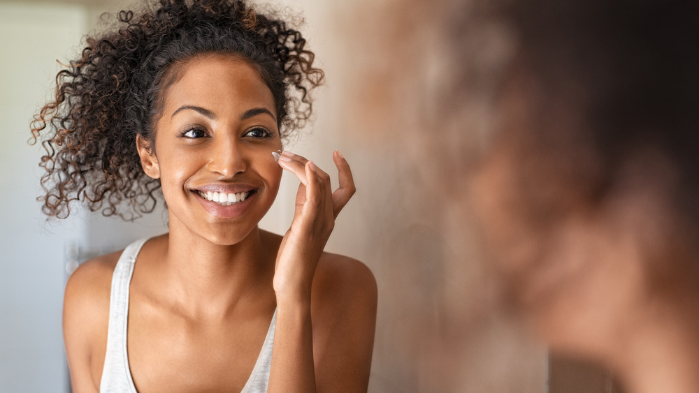 Woman applying moisturizer to her cheek