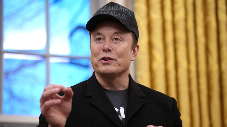 Elon Musk wears a black MAGA hat