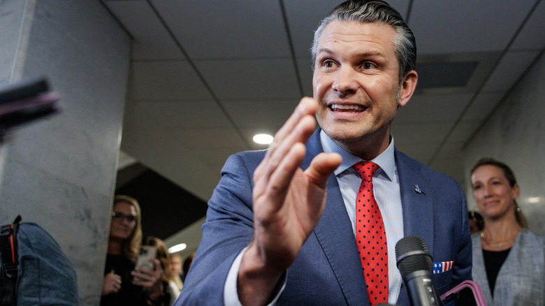 Pete Hegseth addressing the press in a red tie