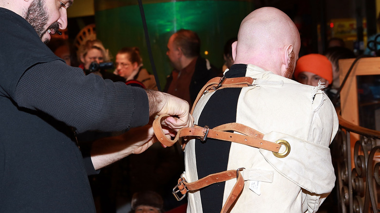 Magician Albert Cadabra being tied into a straightjacket