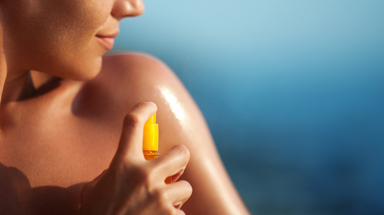 Woman spraying sunscreen on arm