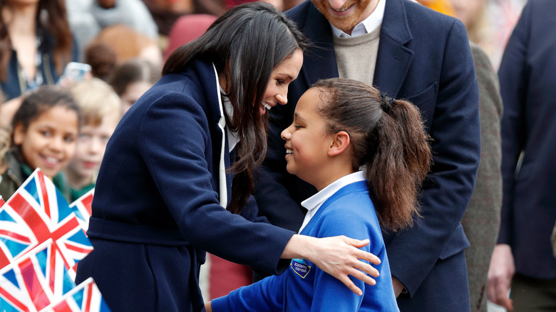 Meghan hugs a student