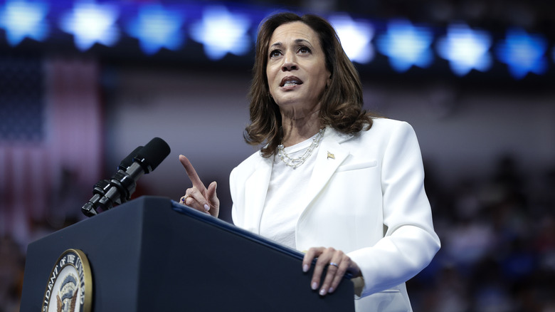 Kamala Harris making speech on podium in white suit