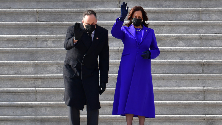 Kamala Harris in purple coat waving next to Doug Emhoff on Inauguration Day