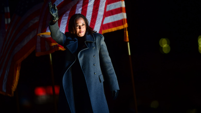 Kamala Harris waving in front of a flag