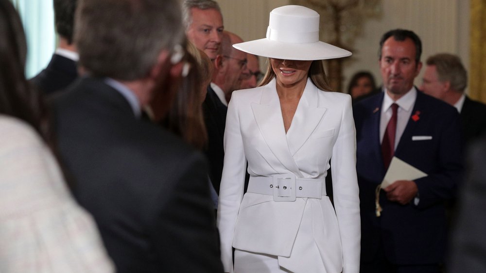 Melania Trump wearing a white hat and outfit