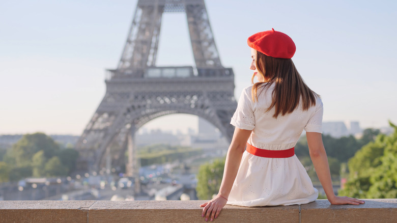 Person in a white dress sitting in front of the Eiffel Tower