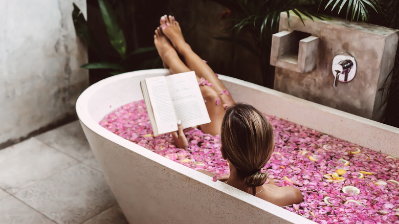 Woman reading a book in a bath in Bali, Indonesia